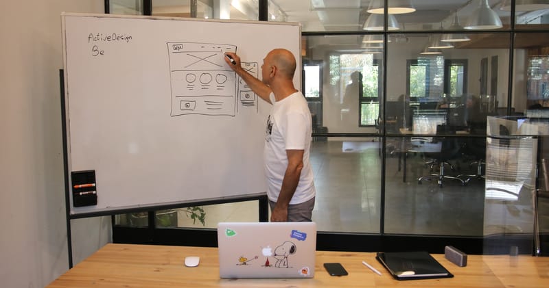 Concentrated male entrepreneur analyzing project standing near whiteboard in modern workspace
