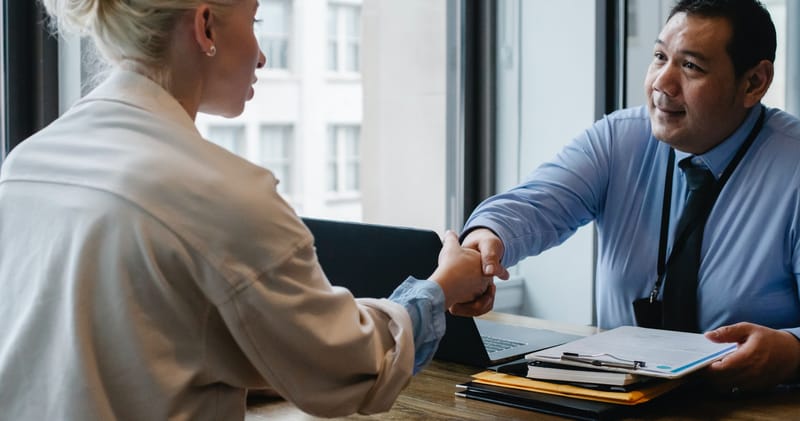 businessman shaking hand of applicant in office
