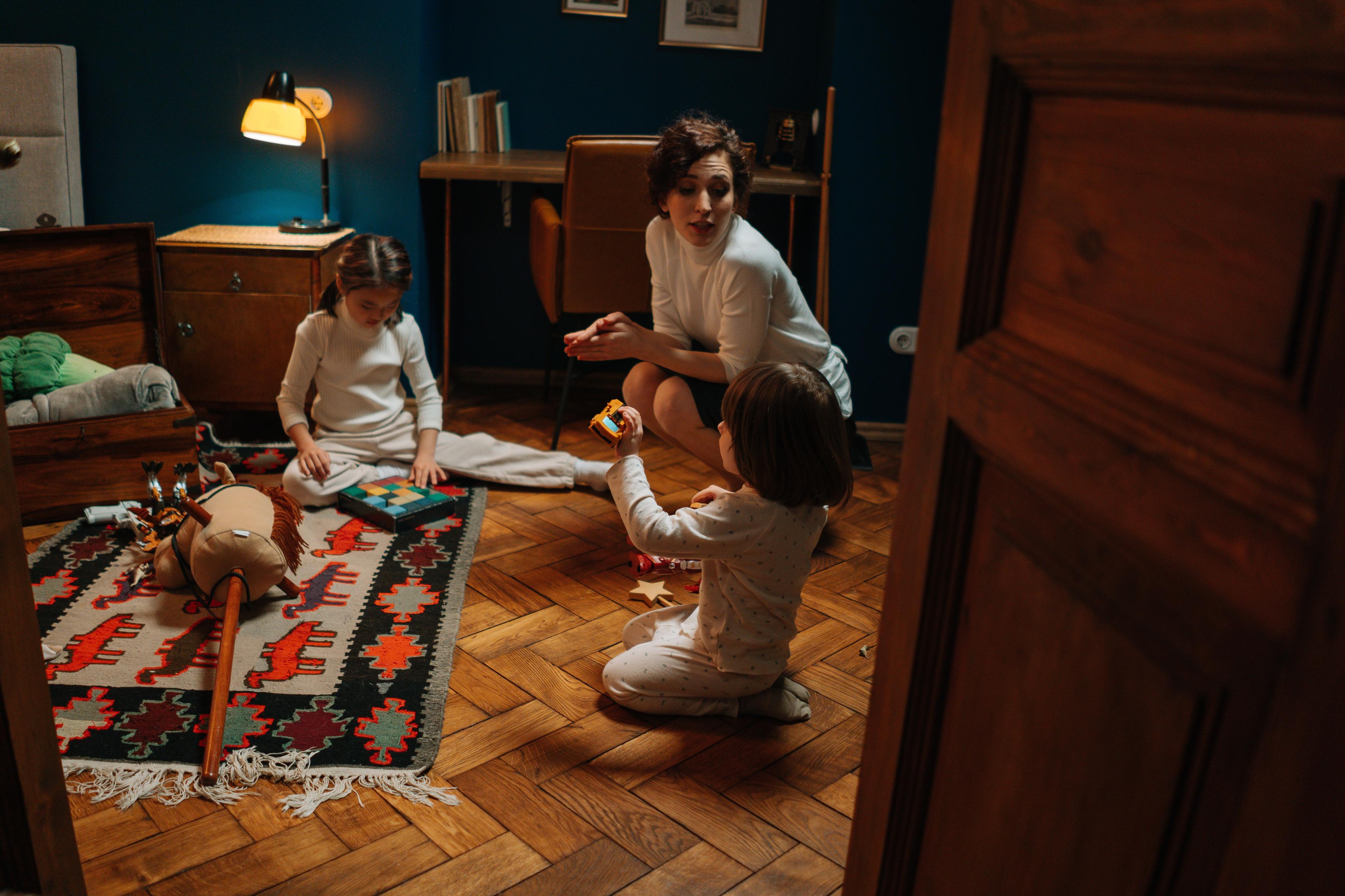 A Woman Sitting on the Floor with Children Playing