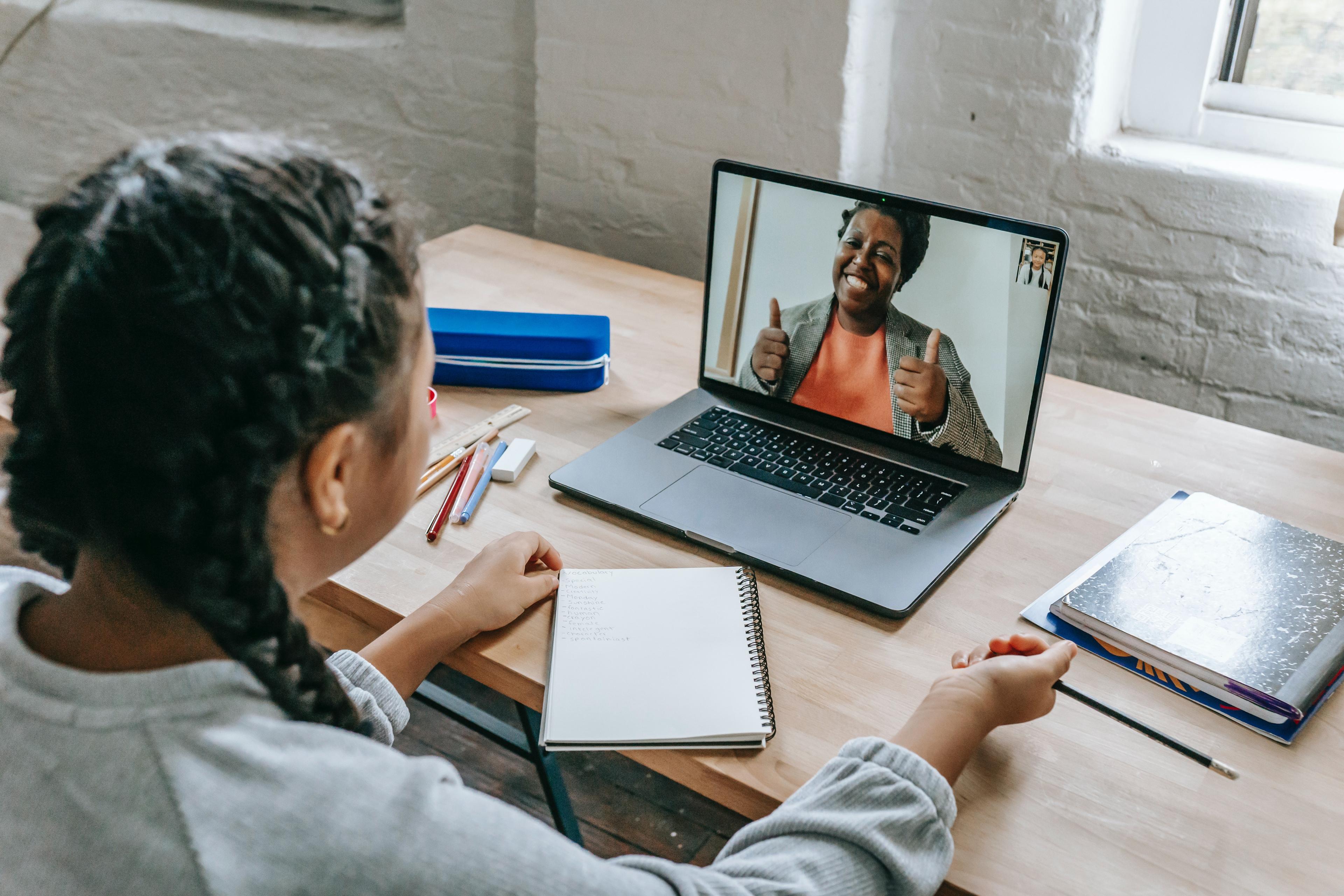 girl having video chat with teacher online on laptop