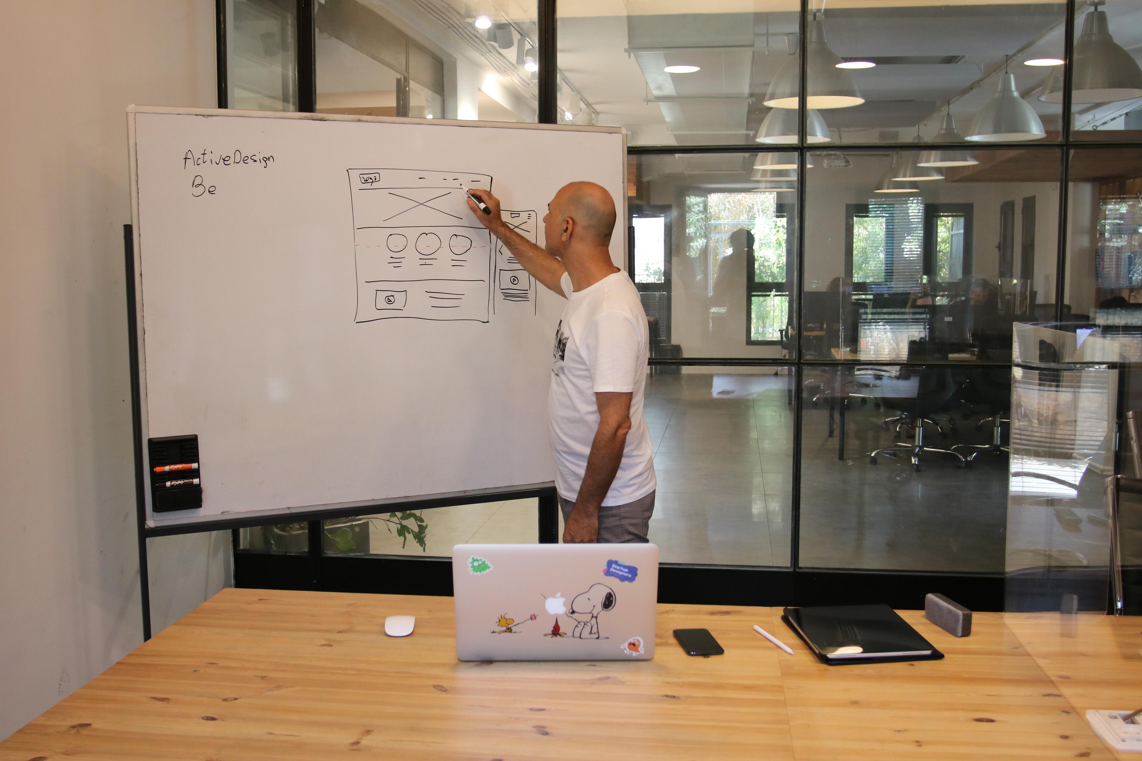 Concentrated male entrepreneur analyzing project standing near whiteboard in modern workspace
