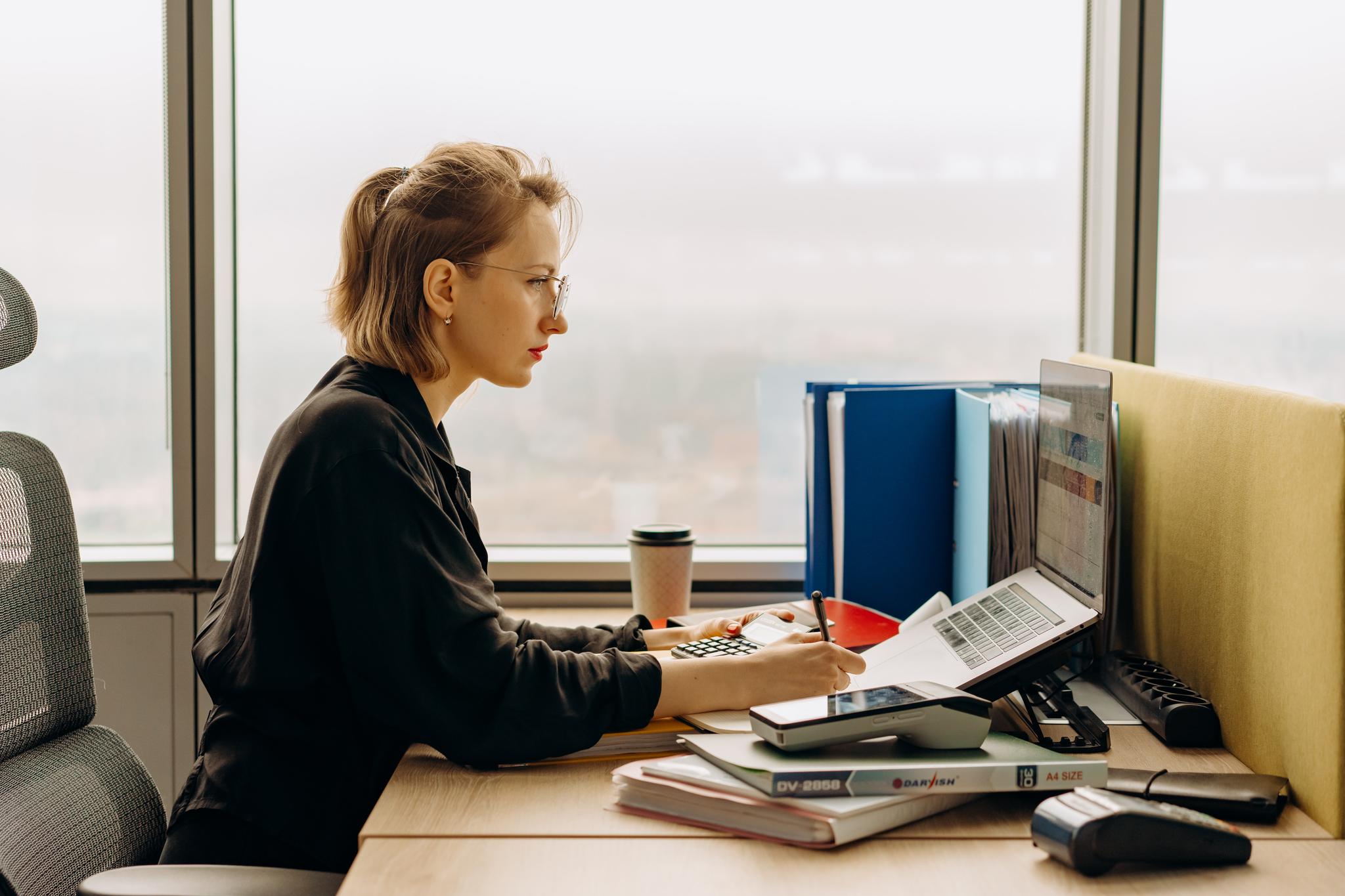 Woman reviewing documents at an office desk, from the guide to becoming an accountant