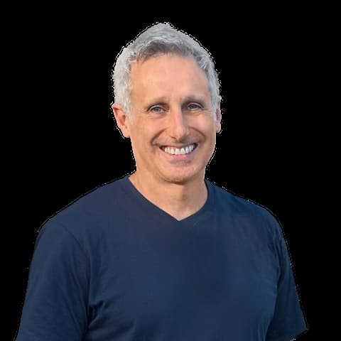 Andrew Henry, grey-haired man smiling in a navy V-neck T-shirt on a white background