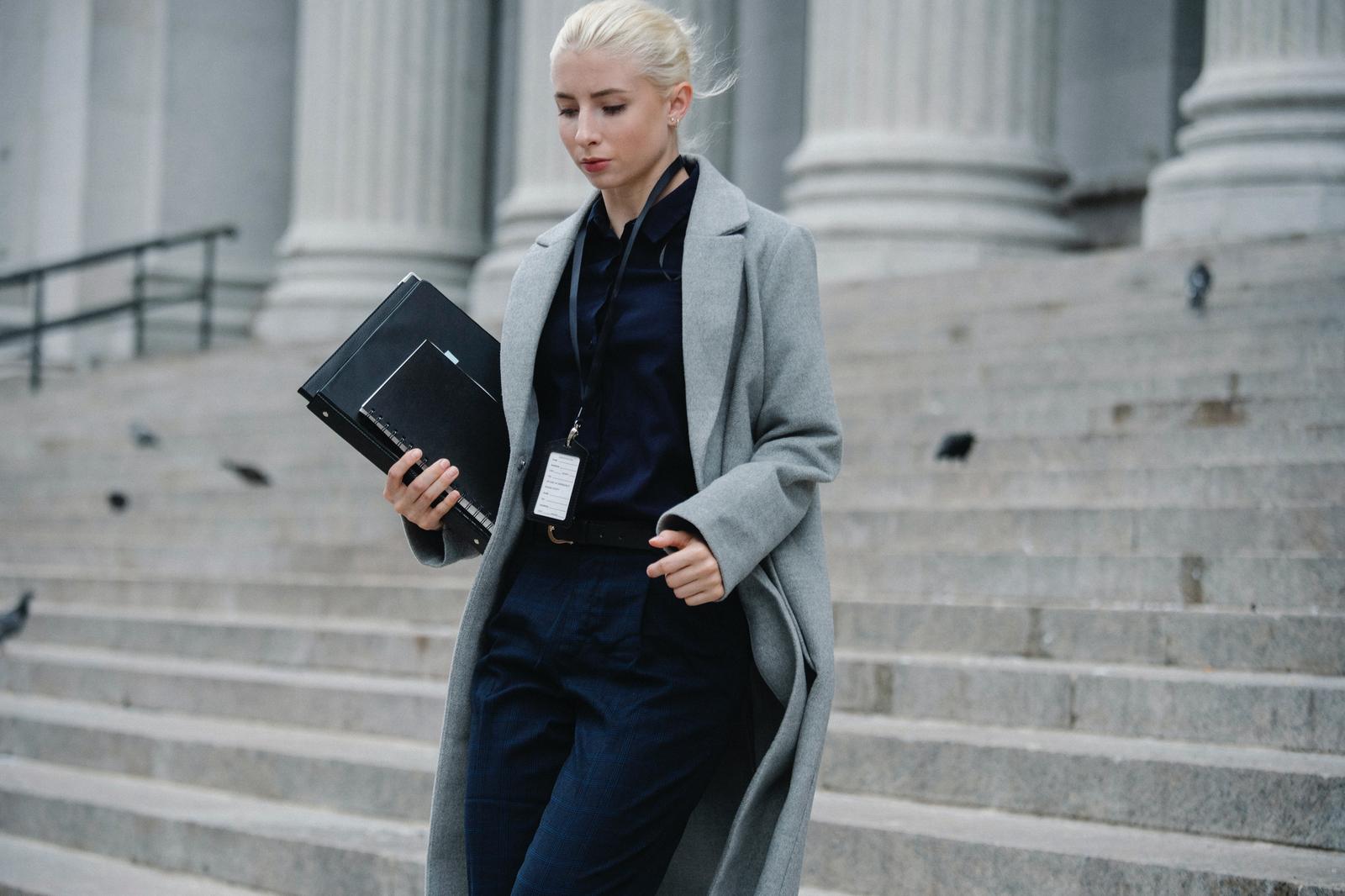 Professional woman carrying a folder down courthouse steps, from our guide to becoming a lawyer
