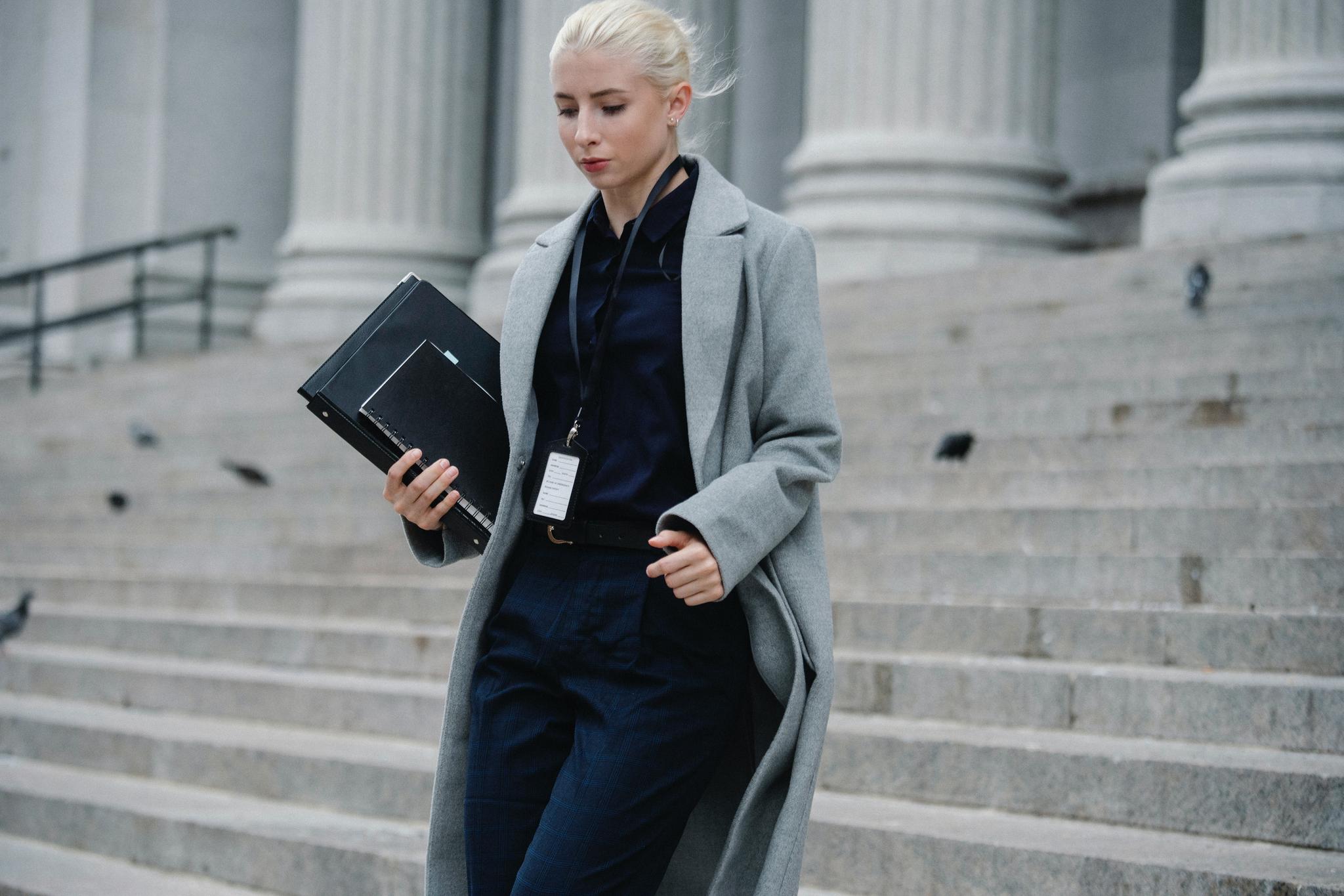 Professional woman carrying a folder down courthouse steps, from our guide to becoming a lawyer