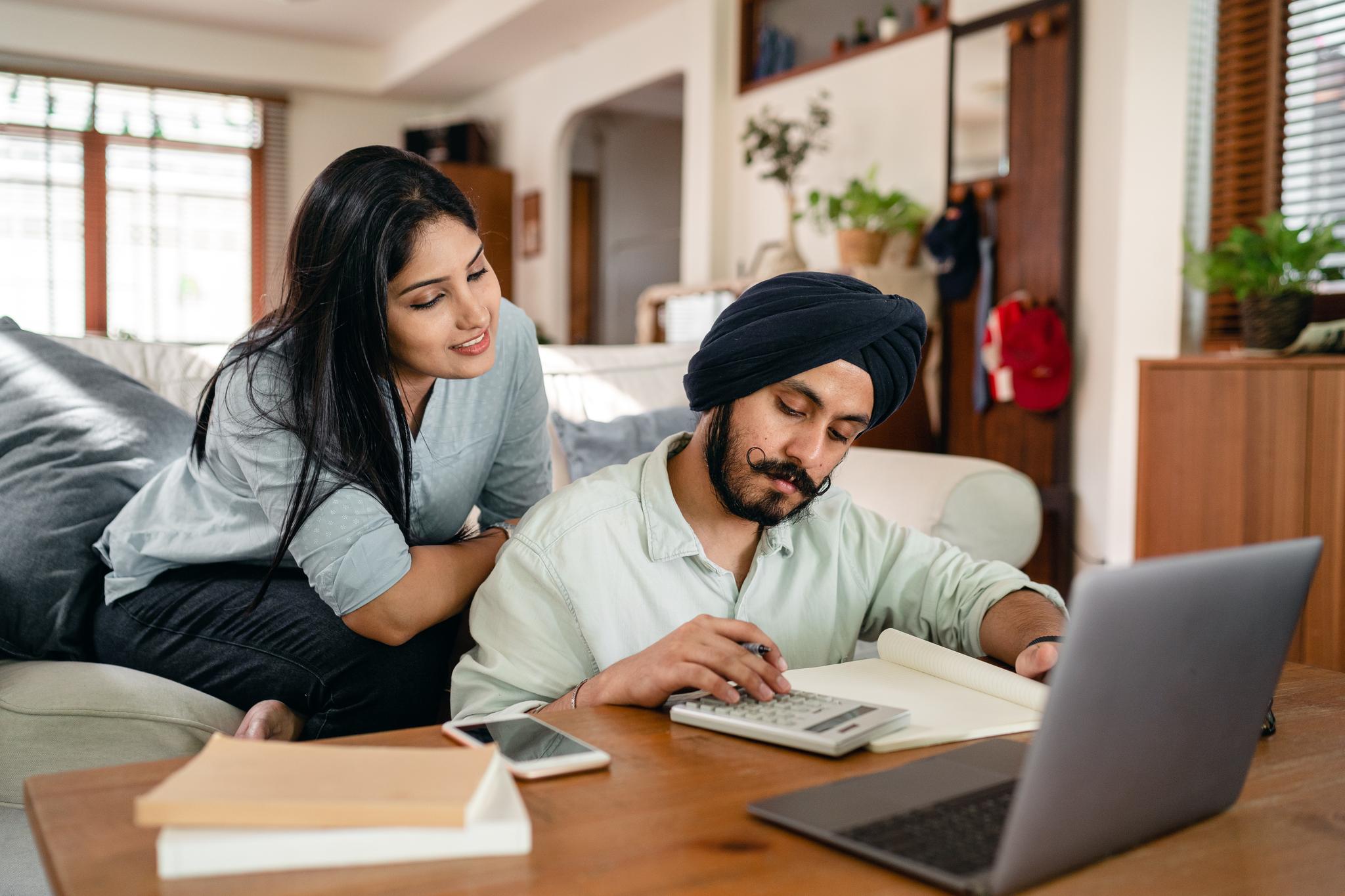 Couple reviewing household finances with a calculator and laptop, from the bookkeeper career guide