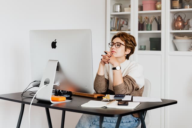 Woman sitting thoughtfully at a desktop computer while planning a career change