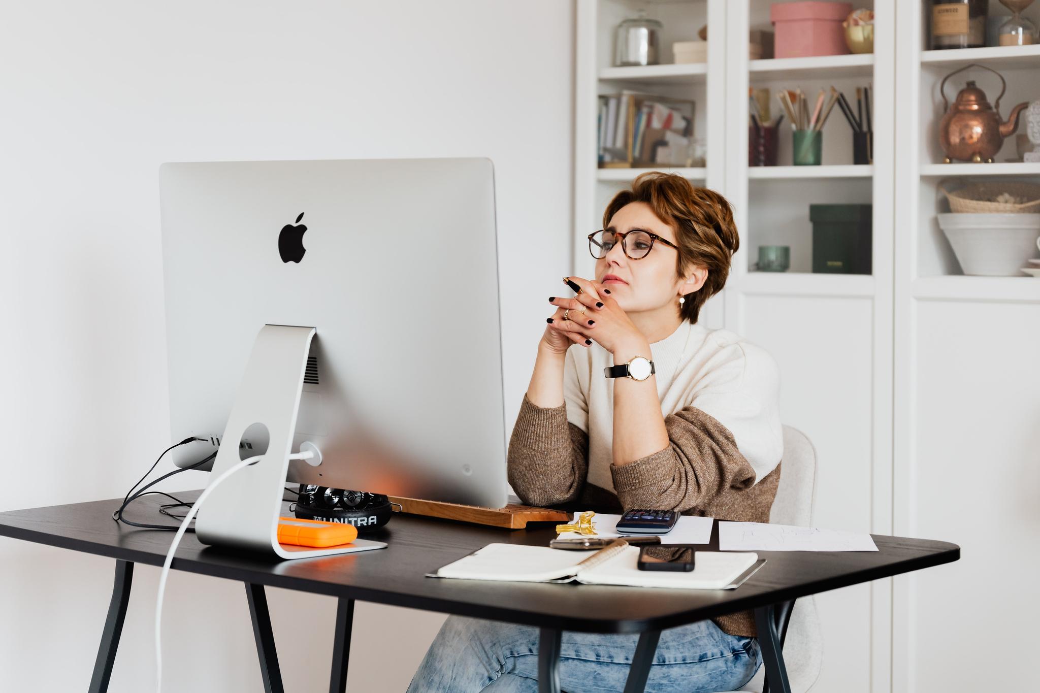 Woman sitting thoughtfully at a desktop computer while planning a career change