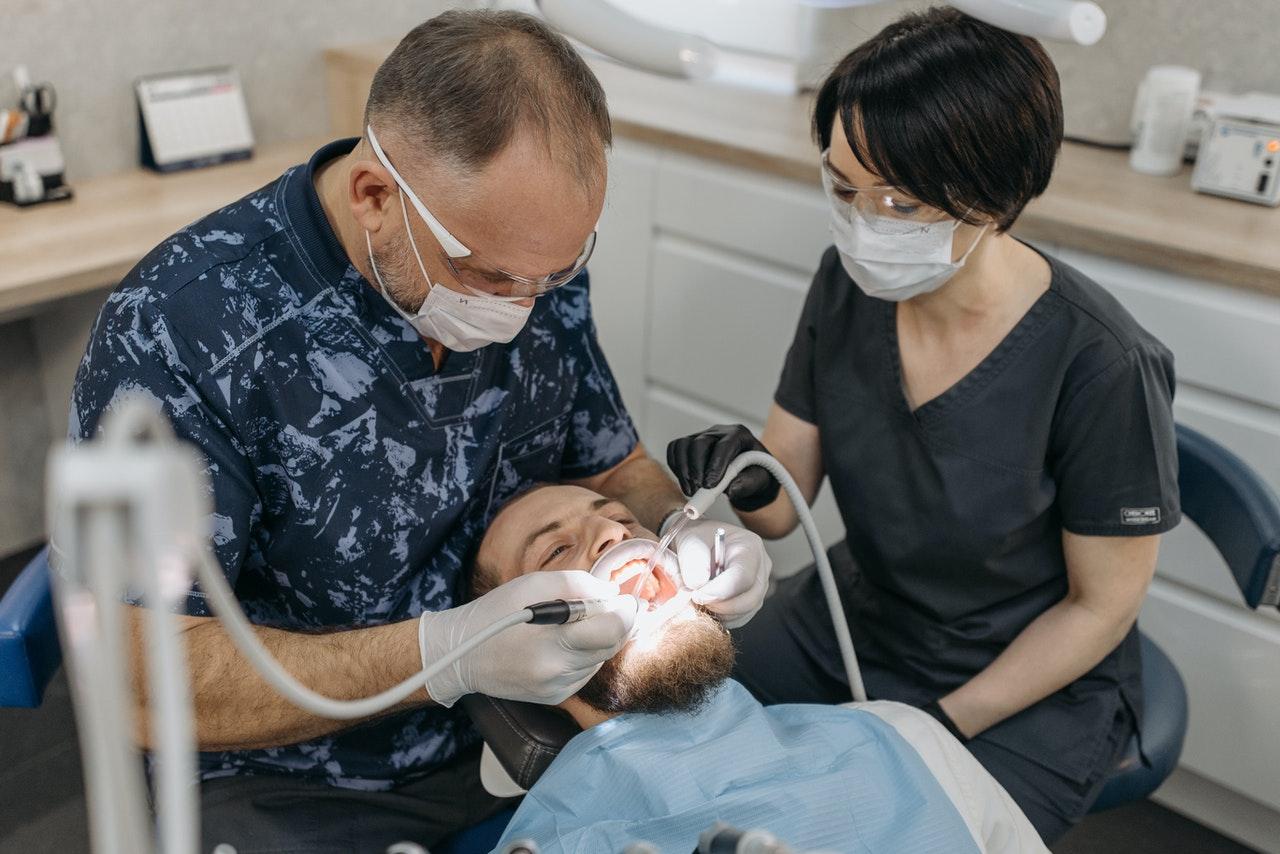 Dentist and masked assistant treating a reclined patient, from the dental assistant skills guide