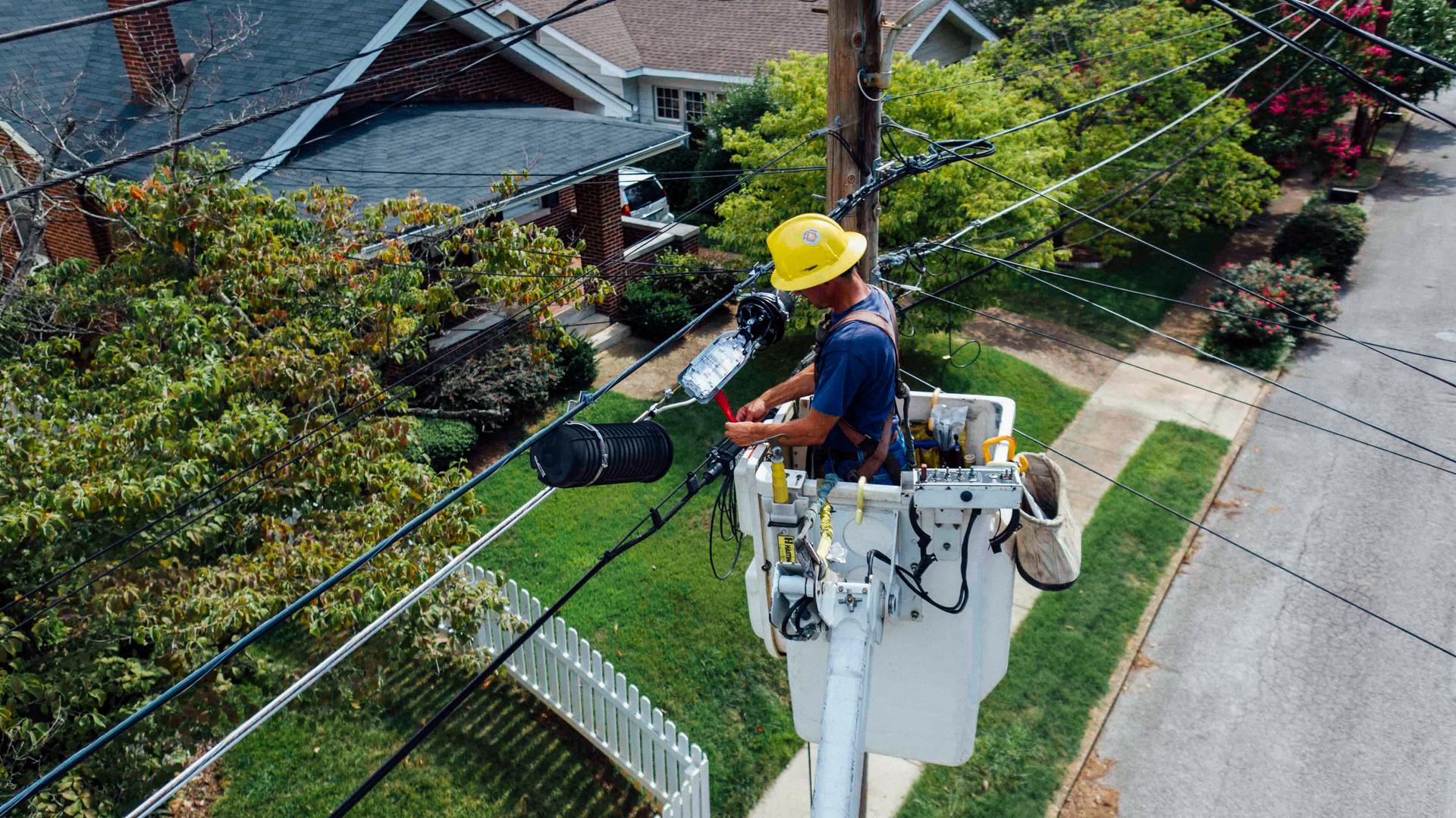 Utility line worker in a bucket lift repairing power lines, from the electrician career guide