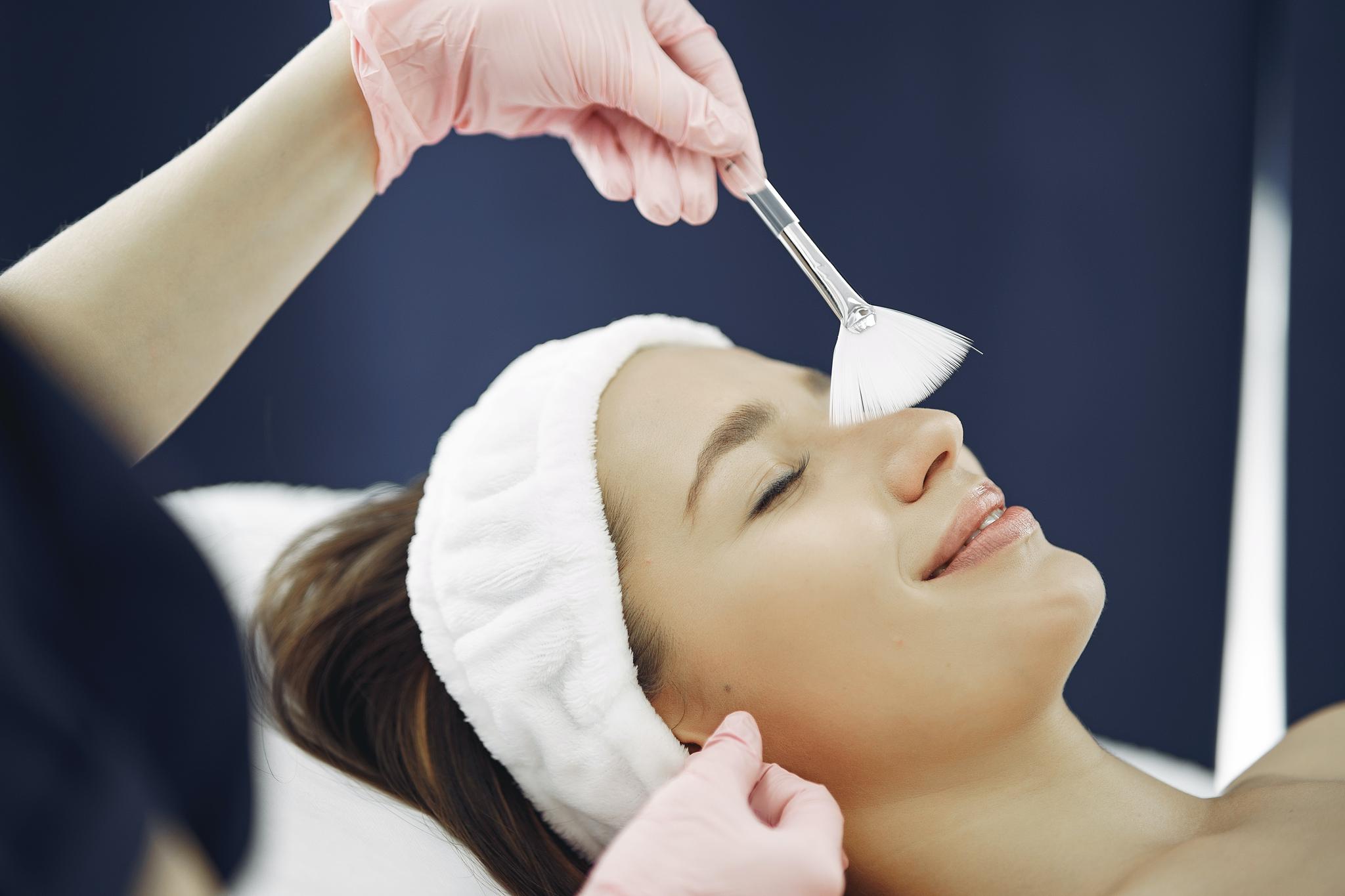 Esthetician applying a facial treatment with a brush to a relaxed client