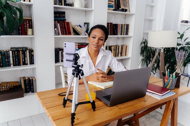 Woman speaking to a phone on a tripod, from the executive assistant interview questions guide
