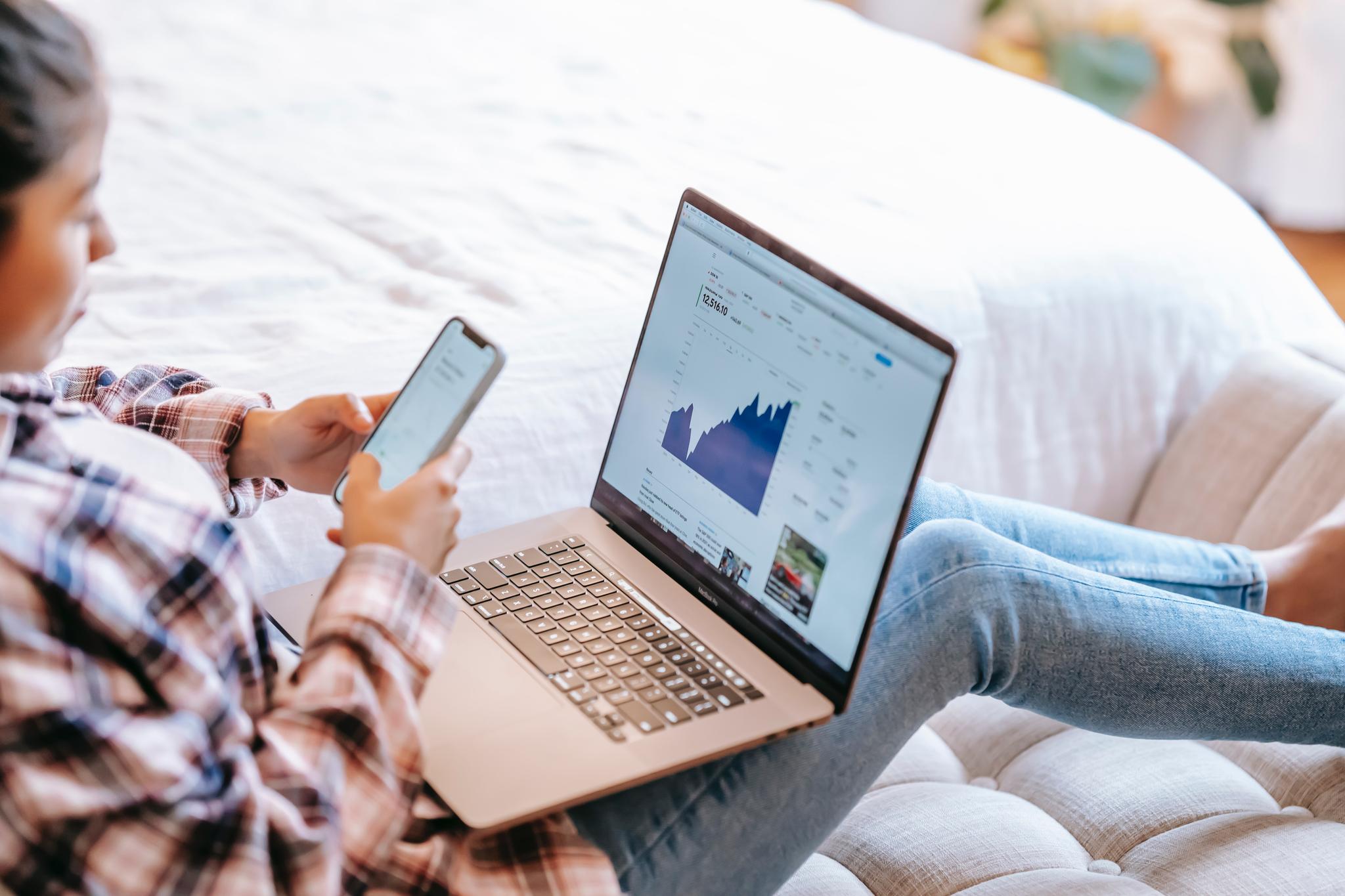 Woman reviewing charts on a laptop and phone, from the financial analyst resume guide