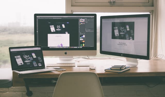 Designer workspace with three screens showing design projects, from the graphic designer resume guide