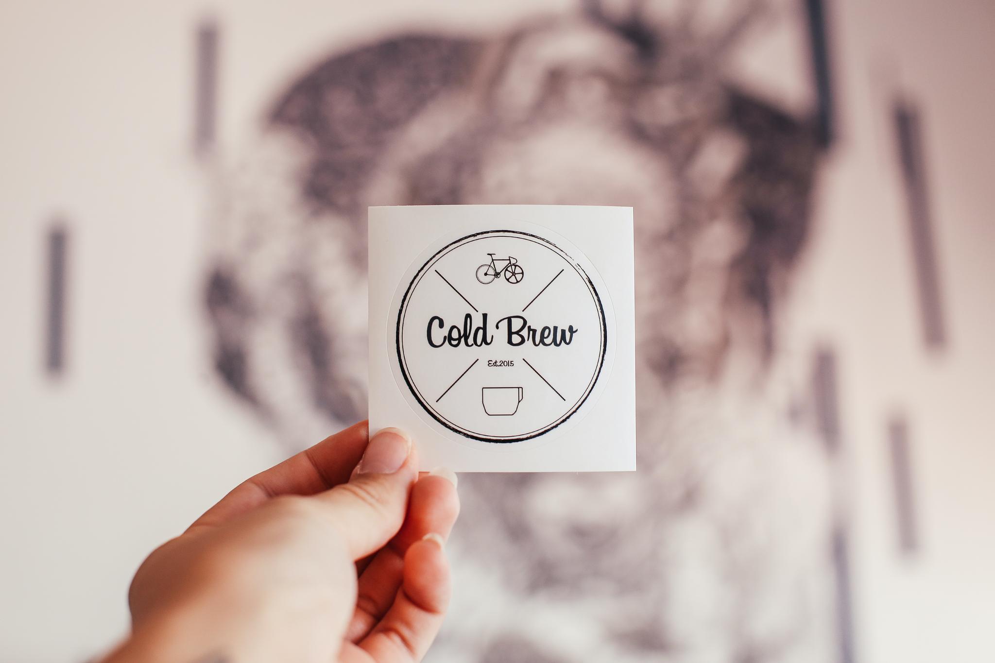 Crop person showing sticker of cafe with inscription