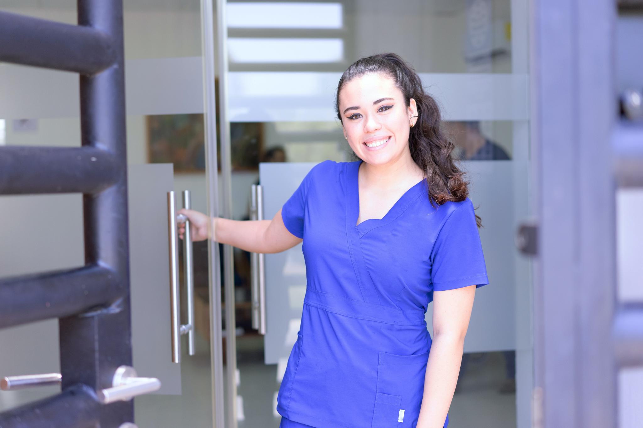 Medical professional in blue scrubs at a clinic door, from the medical assistant resume guide