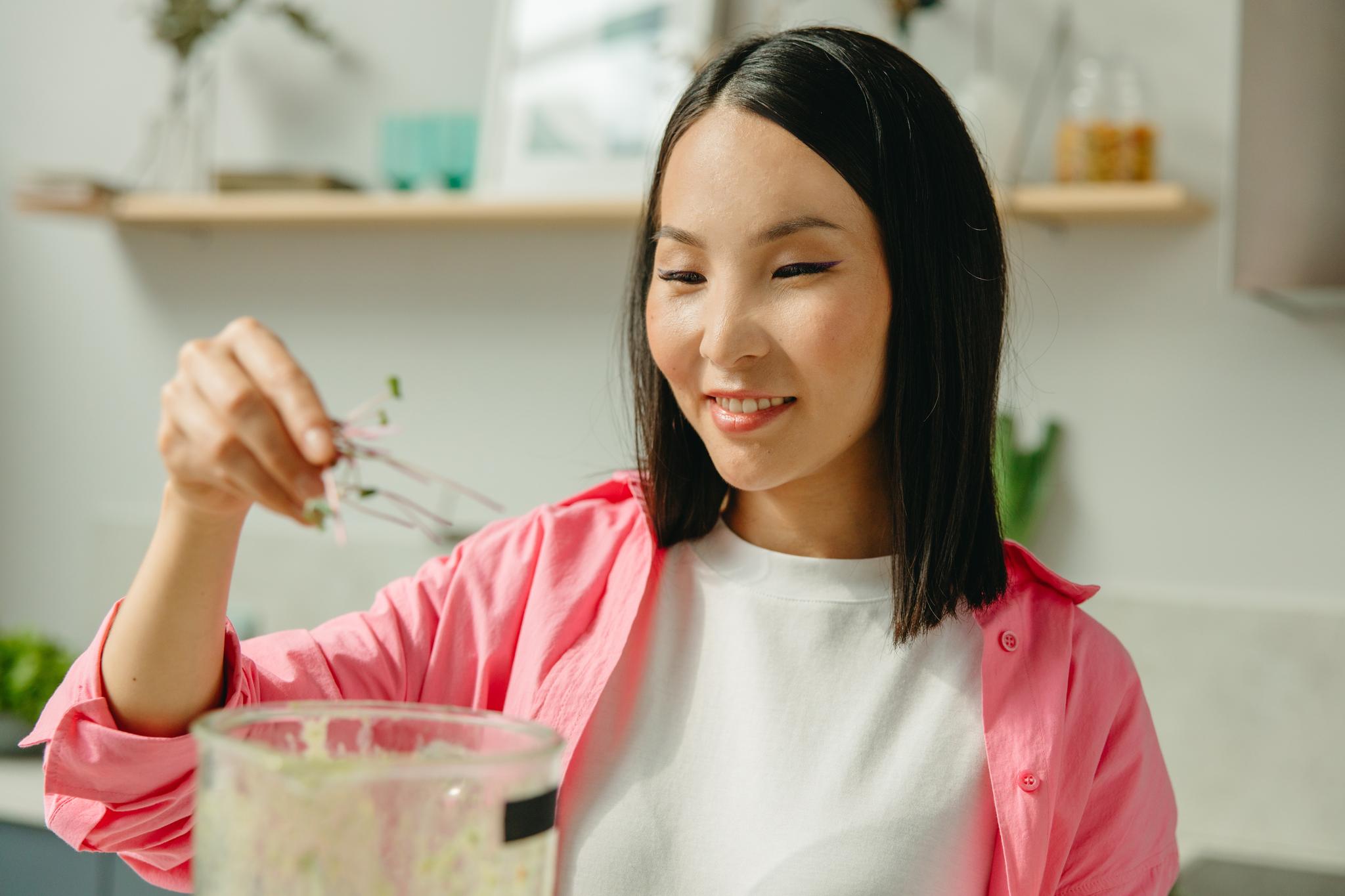Woman adding ingredients to a blender, from the nutritionist career guide