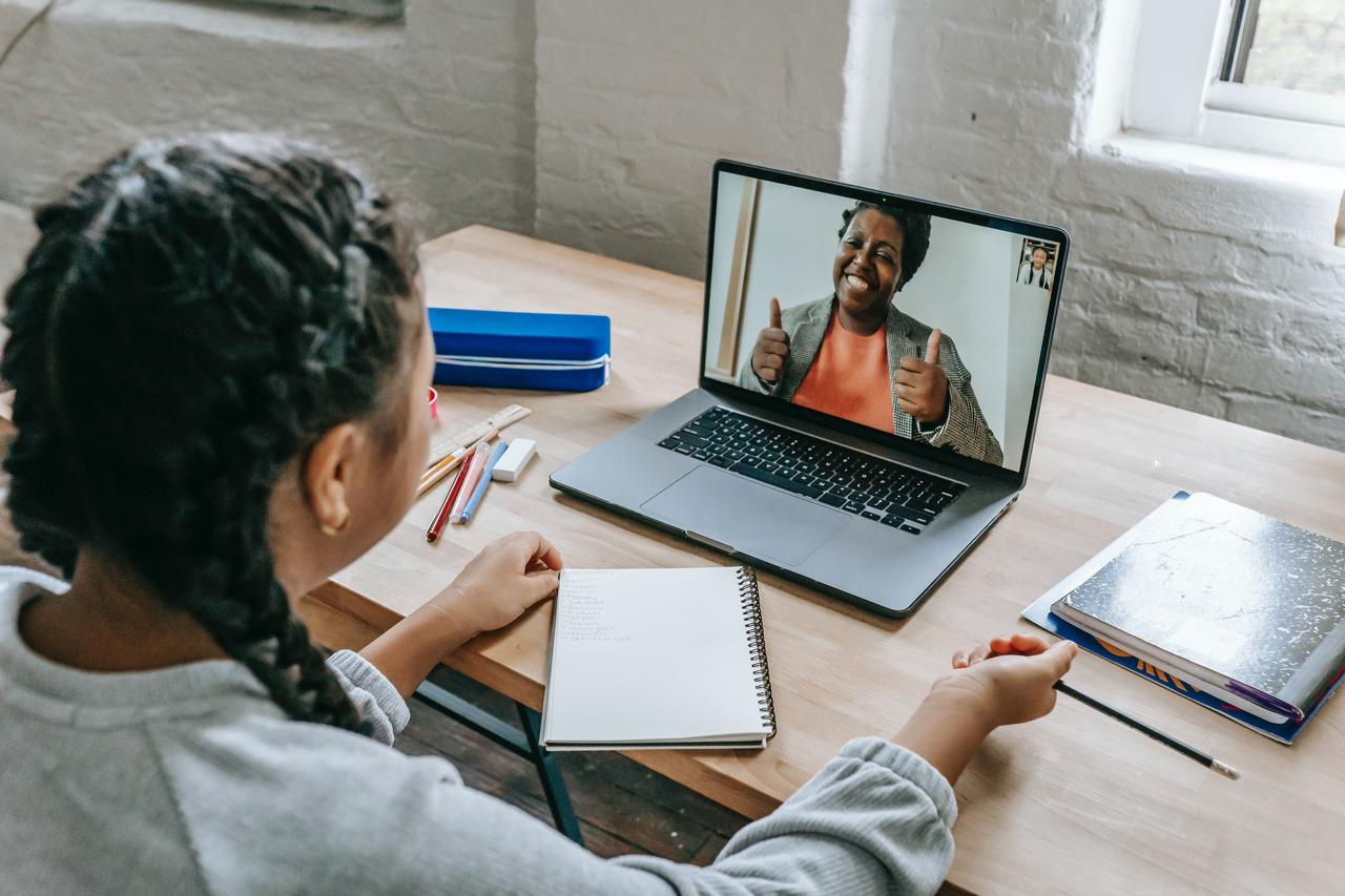 girl having video chat with teacher online on laptop