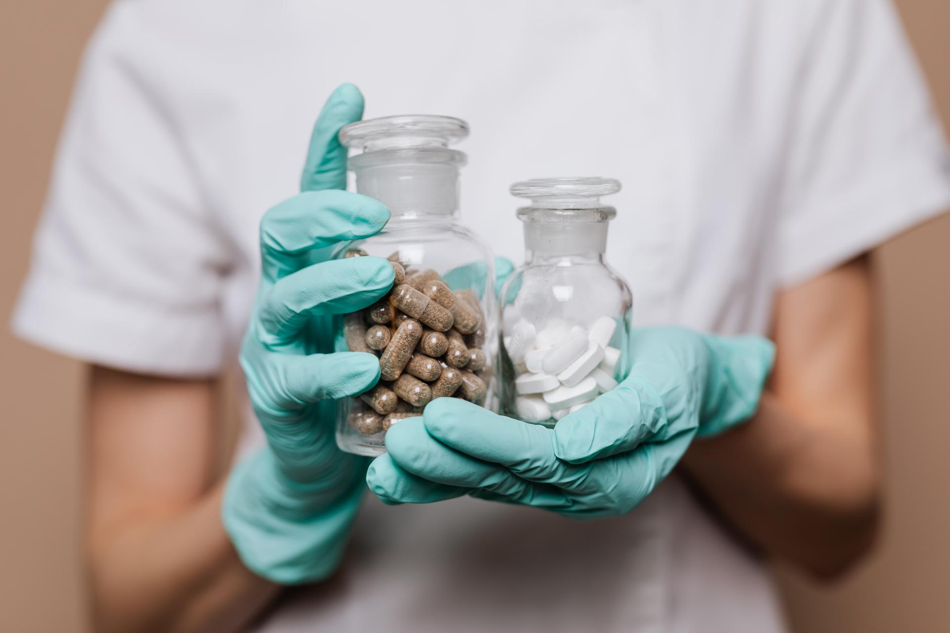Healthcare worker holding jars of pills and capsules, from the pharmacist career guide
