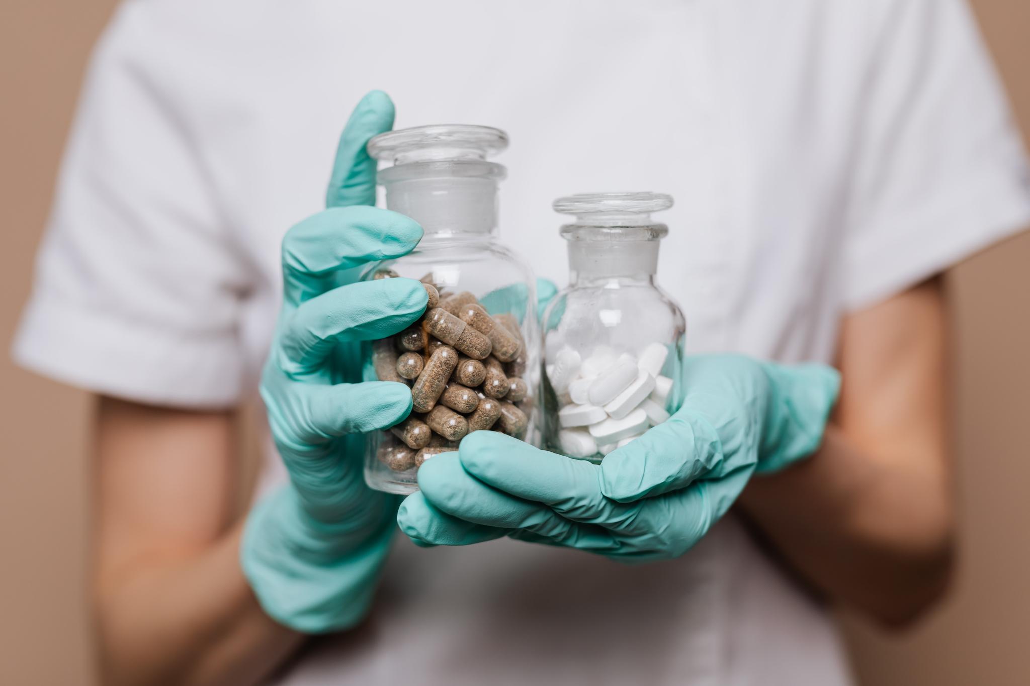 Healthcare worker holding jars of pills and capsules, from the pharmacist career guide