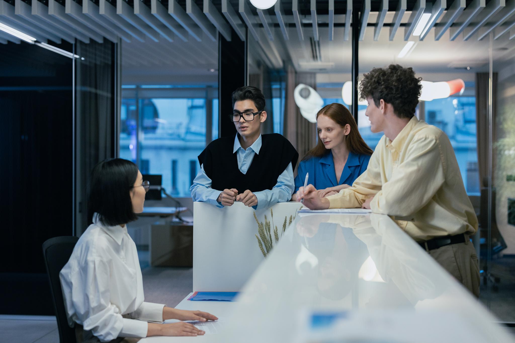 Four colleagues talking around a table in a modern office, from the receptionist resume guide