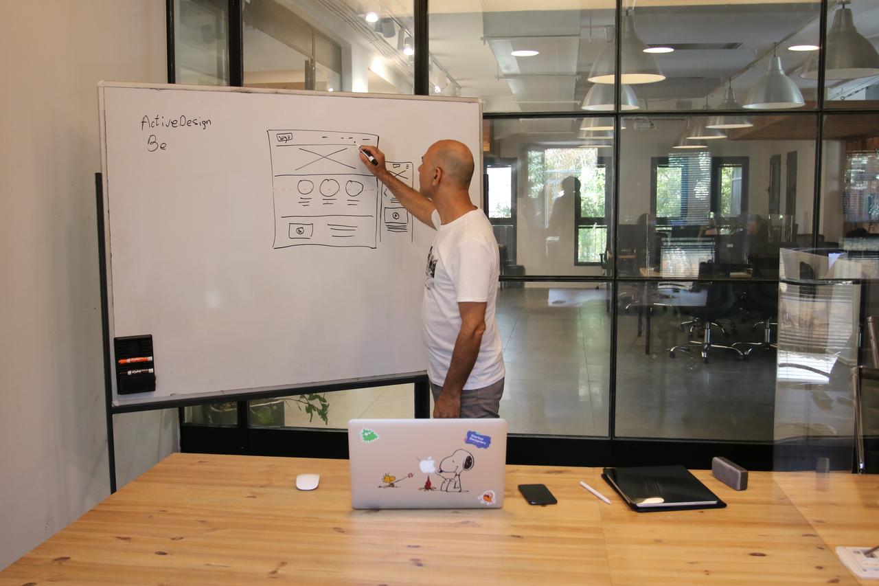 Concentrated male entrepreneur analyzing project standing near whiteboard in modern workspace