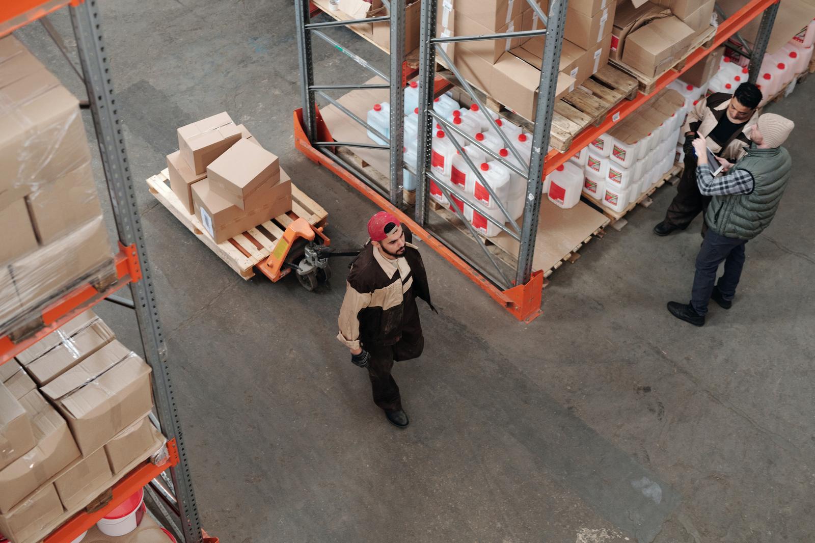 Overhead view of warehouse workers moving pallets and boxes between tall storage racks