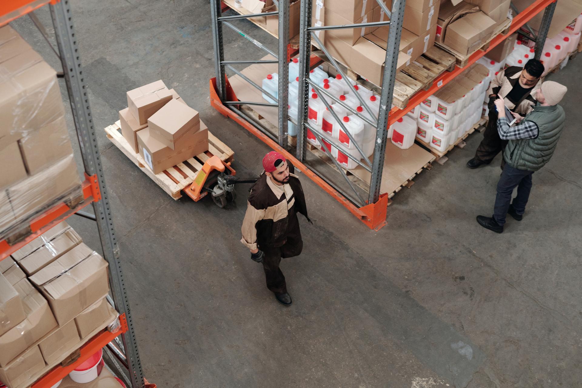 Overhead view of warehouse workers moving pallets and boxes between tall storage racks
