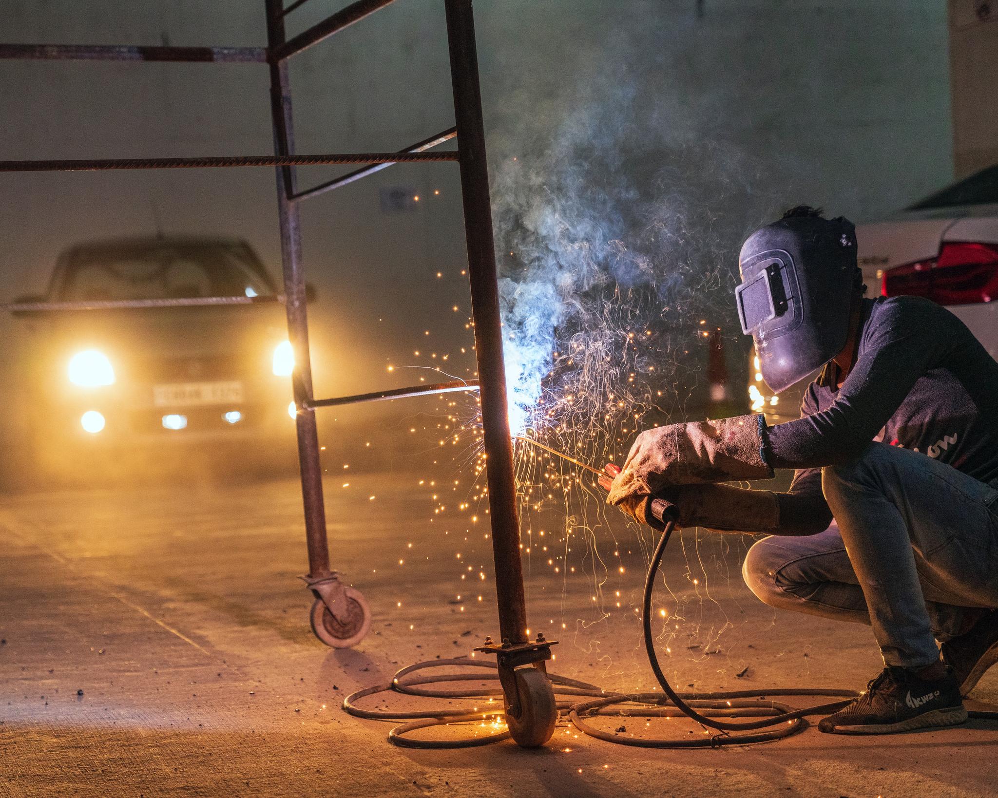 Welder crouching outdoors at night with sparks flying, from the welder career guide